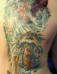 Großflächiges japanisches Rückentattoo einer Frau. Es zeigt zwei detailreiche Koi-Karpfen in einem wilden Wasserfall: unten ein gold-orangefarbener Koi in stürmischen, blau-türkisen Wellen, oben ein rot-violett schattierter Koi nahe einer Lotusblüte. Der Hintergrund ist mit traditioneller Gischt und einer gelben Blüte verziert, gestochen von BIG WAVE TATTOO PRIVATE & ART.