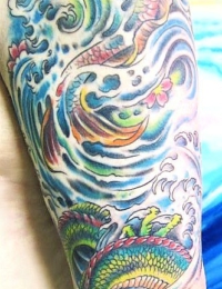 Vollständig tätowierter Arm (Full Sleeve) im farbigen japanischen Irezumi-Stil. Auf dem Oberarm befindet sich ein rot-oranger Koi-Karpfen in blau-türkisen Wellen mit kleinen Kirschblüten. Der Unterarm zeigt einen detailreichen grünen Drachen (Ryu) mit gelben Schuppen, gestochen von BIG WAVE TATTOO PRIVATE & ART.