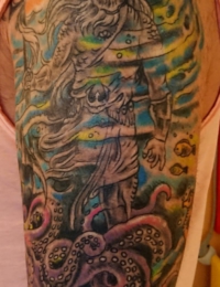• Farbenfrohes Traditional Tattoo auf dem Oberarm mit dem Meeresgott Neptun, einer großen Welle und detaillierten Oktopus-Tentakeln im Old-School-Stil, gestochen von BIG WAVE TATTOO PRIVATE & ART in Essen.